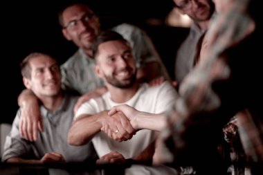 Ofis masasında el sıkışmaktan mutlu çalışanlar.