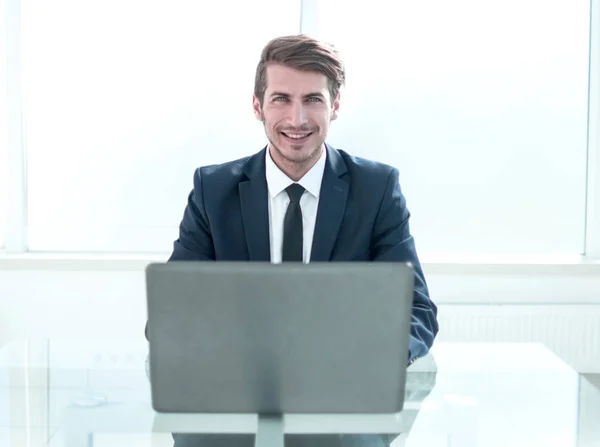 Уверенный бизнесмен, сидящий за столом в просторном офисе — стоковое фото