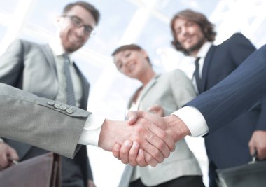 İş ortaklarının el sıkışması ön planda.