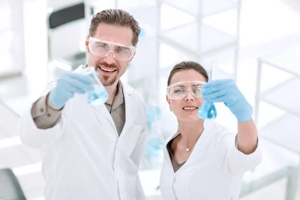 Вчений і асистент з трубками, стоячи в лабораторії — стокове фото