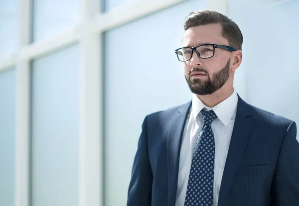 Seriöser Geschäftsmann steht in einem hellen Büro — Stockfoto