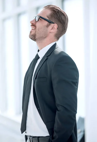 Side view.confident businessman standing near the office window. — Stock Photo, Image