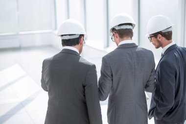 İşadamı ve mimarlar yeni projenin çizimlerini tartışıyor