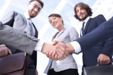 İş ortaklarının el sıkışması ön planda.