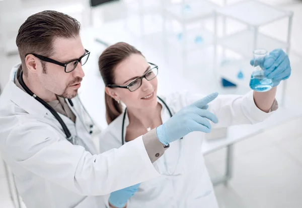 Close up. researchers are discussing the liquid in the flask — стоковое фото