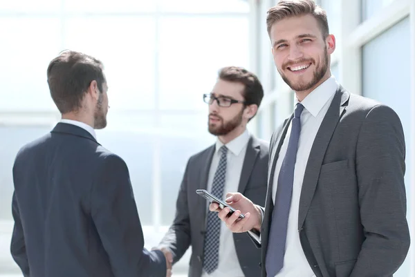 Mujer de negocios sonriente con teléfono inteligente de pie en la oficina — Foto de Stock