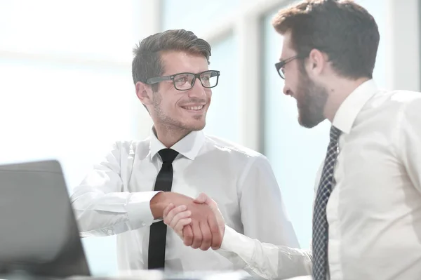 Apretón de manos colegas de negocios sentados en su escritorio — Foto de Stock