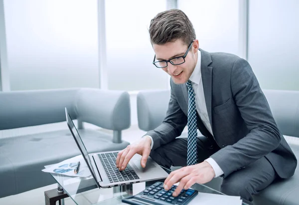 Jovem empresário usando calculadora e laptop — Fotografia de Stock