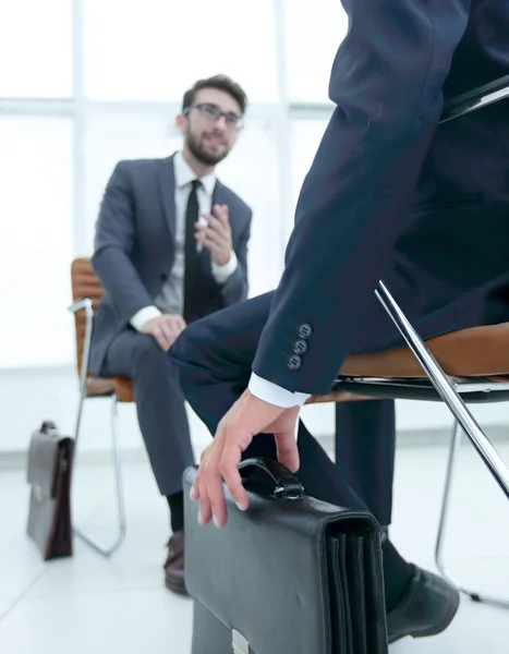 Человек, сидящий на стуле в офисе, слушает бизнесмена — стоковое фото