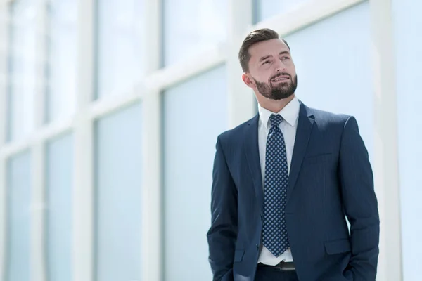 Dreaming businessman standing in a bright office. — Stock Photo, Image