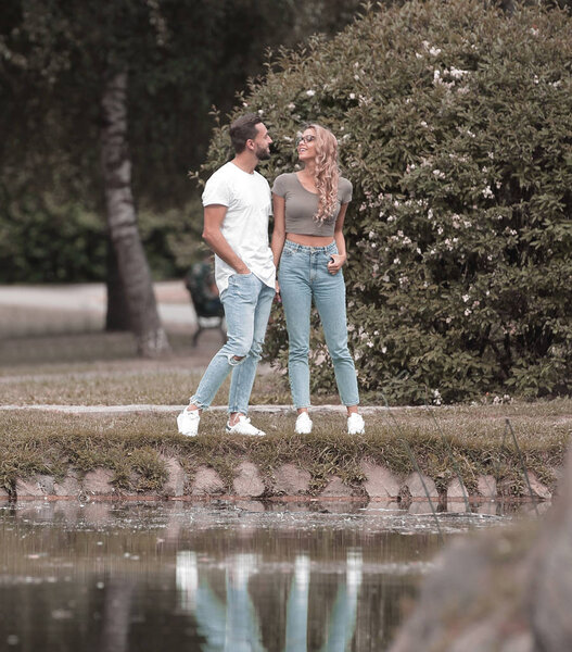Влюбленная пара, стоящая на траве у озера
