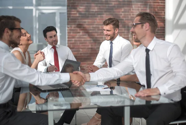 Sonrientes socios de negocios estrechando la mano en la mesa de negociaciones —  Fotos de Stock