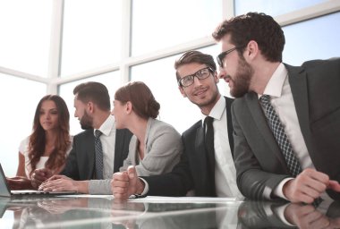 İş ekibi ofisteki masada oturuyor.