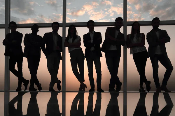 Силует бізнес-команди, що стоїть поруч з офісним вікном — стокове фото