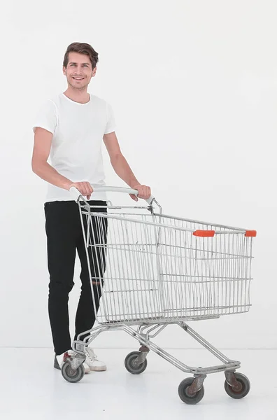 Mladý muž tlačí prázdný nákupní vozík — Stock fotografie