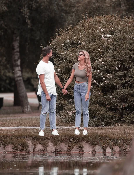 Älskande par stående nära en sjö i en stad Park — Stockfoto