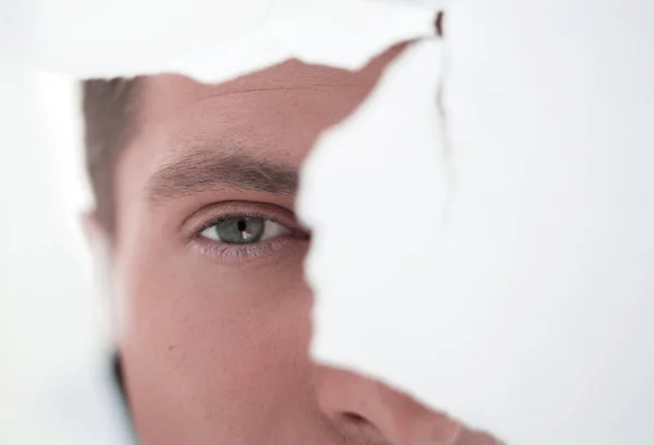 Homme d'affaires attentif regardant à travers un trou dans un mur de papier. — Photo