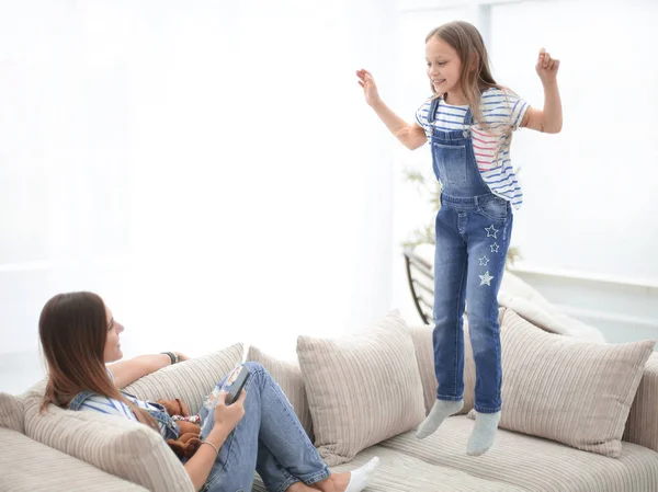 Mamá y su hija pequeña están jugando en el sofá en la sala de estar —  Fotos de Stock