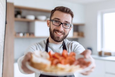 Çekici bir adamın ellerinde bir tabak sandviç.