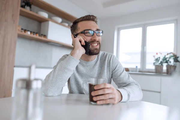 Atractivo hombre hablando en su teléfono inteligente durante el desayuno — Foto de Stock