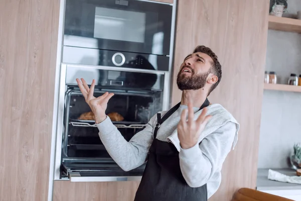 Uomo sorpreso in piedi vicino al forno con croissant bruciati. — Foto Stock