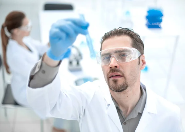 Close up.smiling cientista olha para o tubo com líquido — Fotografia de Stock