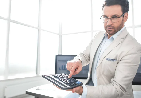 Selbstbewusster Geschäftsmann zeigt auf Taschenrechner — Stockfoto