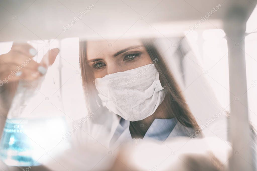 close up. woman doctor in protective mask with flask
