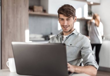 Genç adam çalışma online mutfak masasında oturuyor