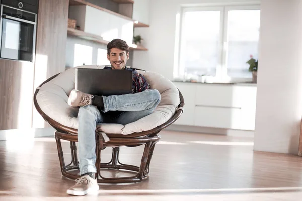 Joven utiliza un ordenador portátil en su apartamento moderno . —  Fotos de Stock