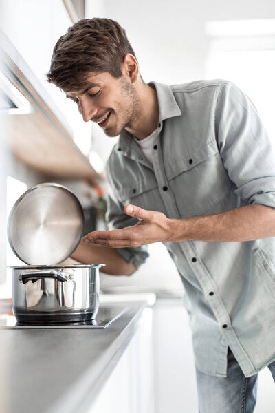 Закрывай. молодой человек смотрит в кастрюлю.