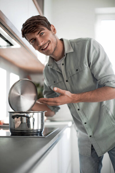 close up. a young man standing near the kitchen stove