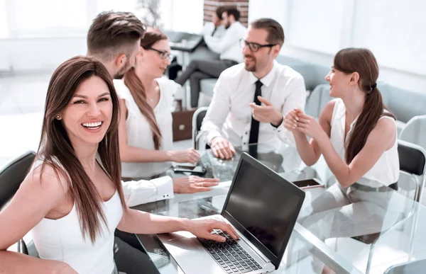 Jonge zakenvrouw en haar collega's zitten aan de kantoor tafel — Stockfoto