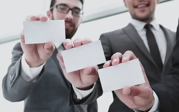 Drie jonge zakenpartners die hun visitekaartjes tonen. — Stockfoto