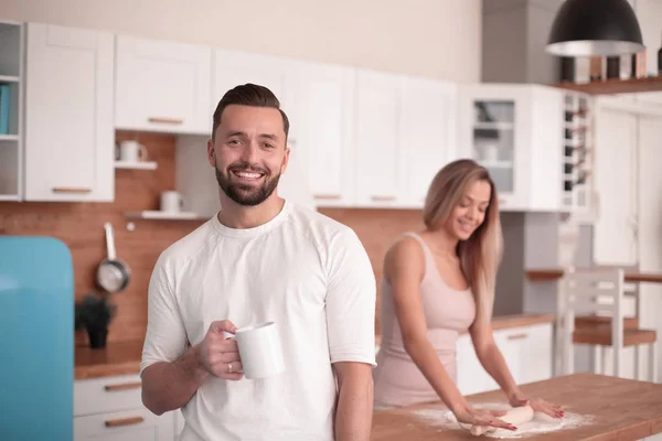 Uomo sorridente con una tazza di tè in piedi in cucina — Foto Stock