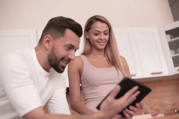 Casal jovem navegando na web com tablet em casa cozinha — Fotografia de Stock