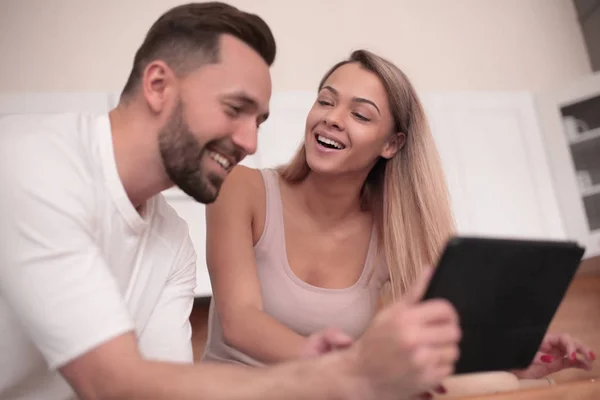 Jovem casal com tablet digital sentado na cozinha — Fotografia de Stock