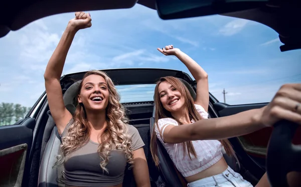 Duas namoradas desfrutando de uma viagem em um carro conversível — Fotografia de Stock