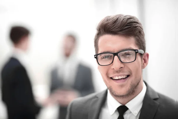 Close up.sorrindo jovem empresário no fundo do escritório — Fotografia de Stock