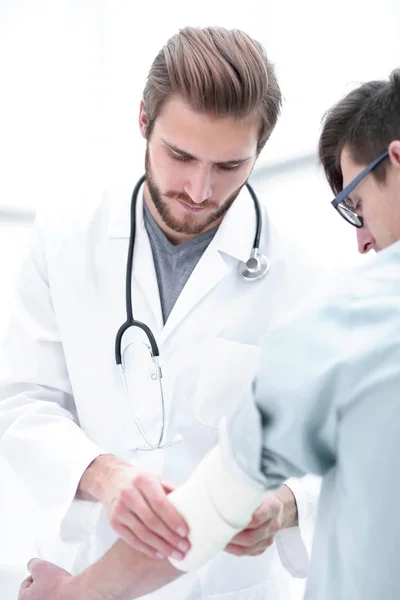 Orthopedist applying bandage onto patients arm — Stock Photo, Image