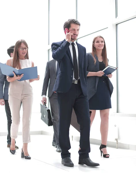 Hombre de negocios serio hablando en el teléfono inteligente mientras está de pie en la oficina — Foto de Stock