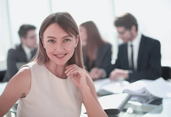 Usměvavá žena sedící u stolu v kanceláři — Stock fotografie