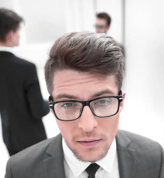 Close up.confident joven hombre de negocios en el fondo borrosa oficina — Foto de Stock