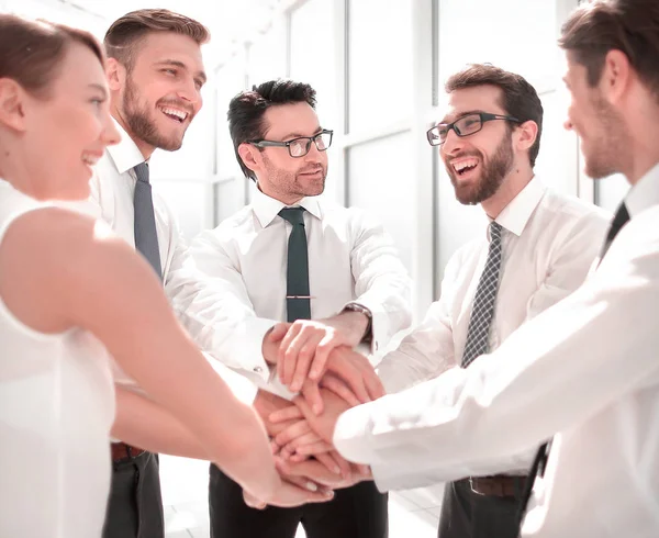 Primer plano. Un equipo de negocios sonriente se para con las manos juntas. — Foto de Stock