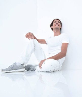 Beyaz bir duvar oturan rüya gibi genç adam.