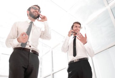 alt view.two başarılı işadamları kendi akıllı telefonlar üzerinde konuşuyor.