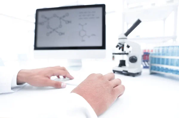 A scientist uses a computer and a microscope — Stock Photo, Image