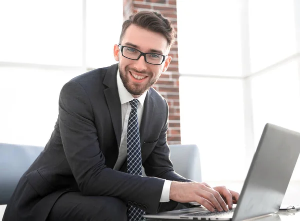 Joven hombre de negocios utilizando el ordenador portátil y sonriendo — Foto de Stock