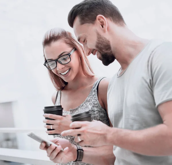 Close up.young casal beber café e ler SMS no smartphone . — Fotografia de Stock