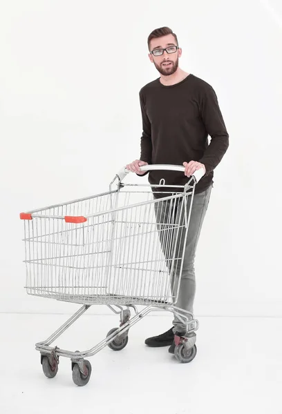 Mladý muž s prázdný nákupní vozík, izolovaných na bílém — Stock fotografie